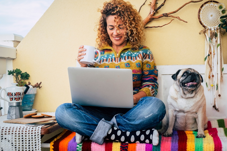 Vrouw op laptop met hondje naast zich