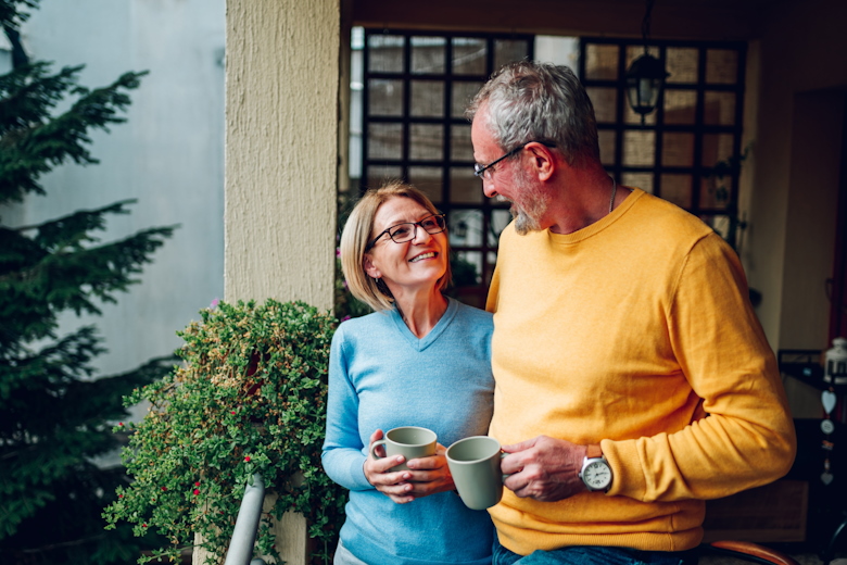 man en vrouw met koffiebeker kijken elkaar lachend aan