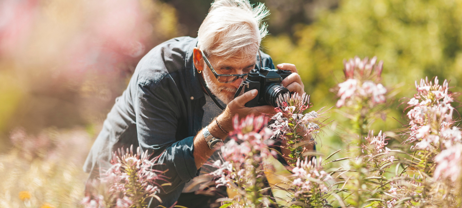 Oude en gepensioneerde man neemt foto van bloemen