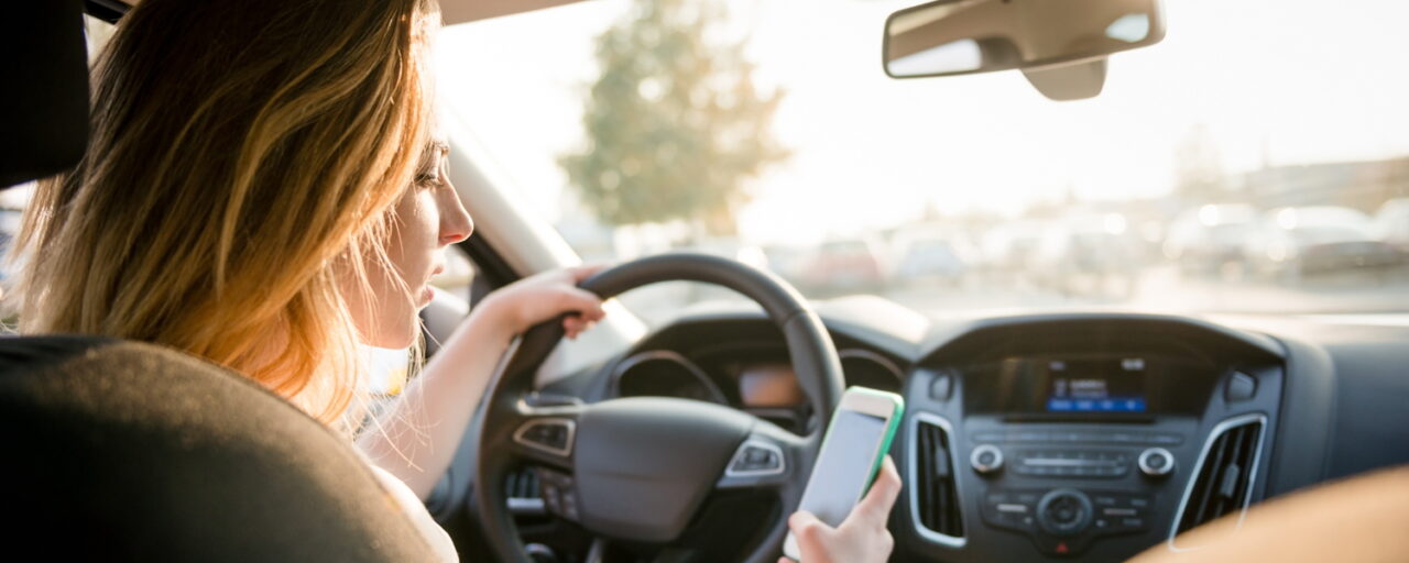 Vrouw in auto afgeleid door mobiele telefoon