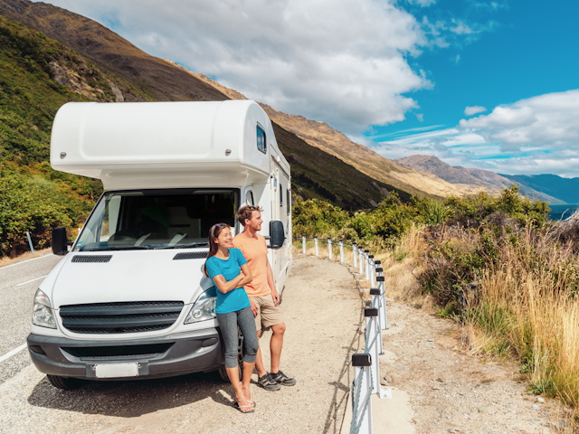 Man en vrouw staan naast camper in de zon