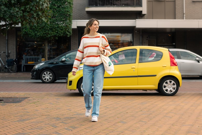 Jonge vrouw loopt weg van gele auto